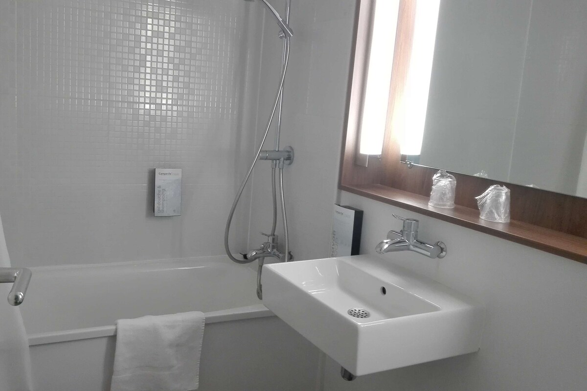 Une salle de bain moderne avec un lavabo blanc, un miroir et une douche.
