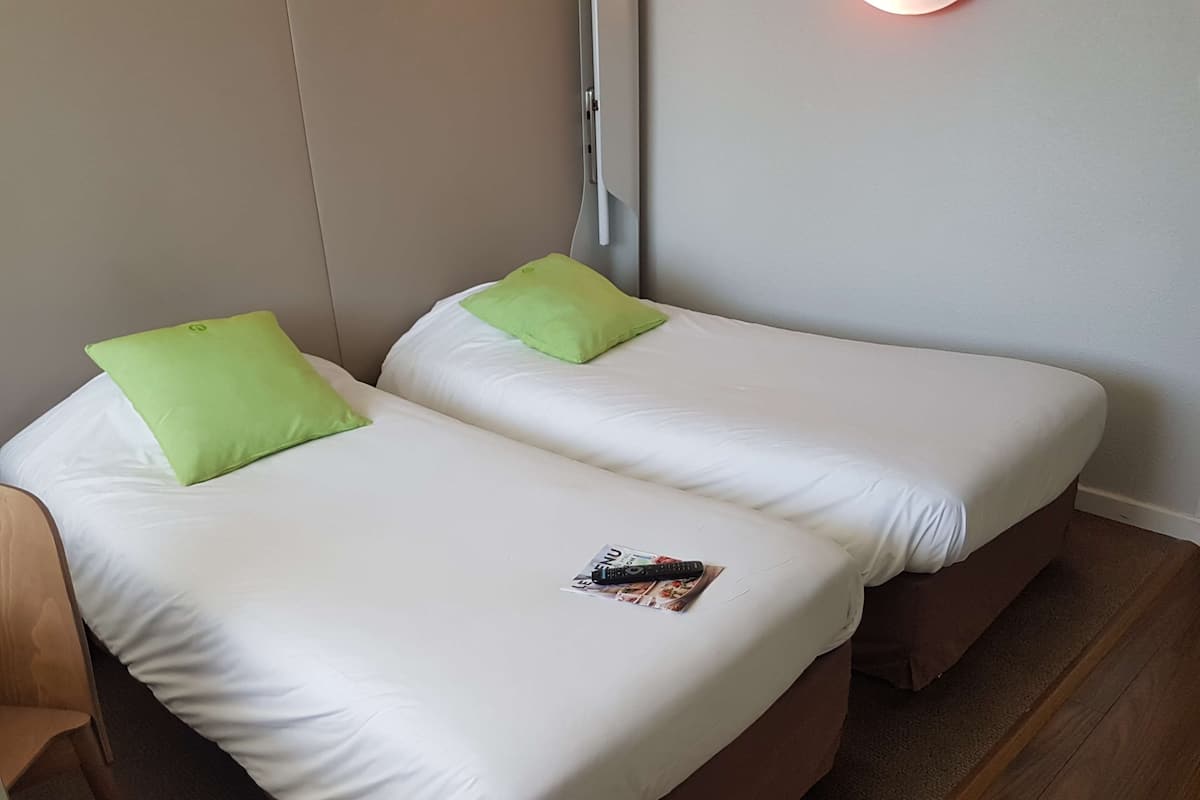 A twin room with two beds, each with white bedding and green pillows.