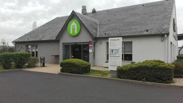 A hotel with a green logo, a sign indicating a restaurant, and a lounge bar.