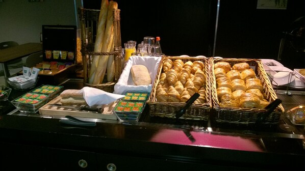 A buffet with various food items including bread, pastries, and condiments. - Campanile Clermont Ferrand Sud - Issoire (Issoire)