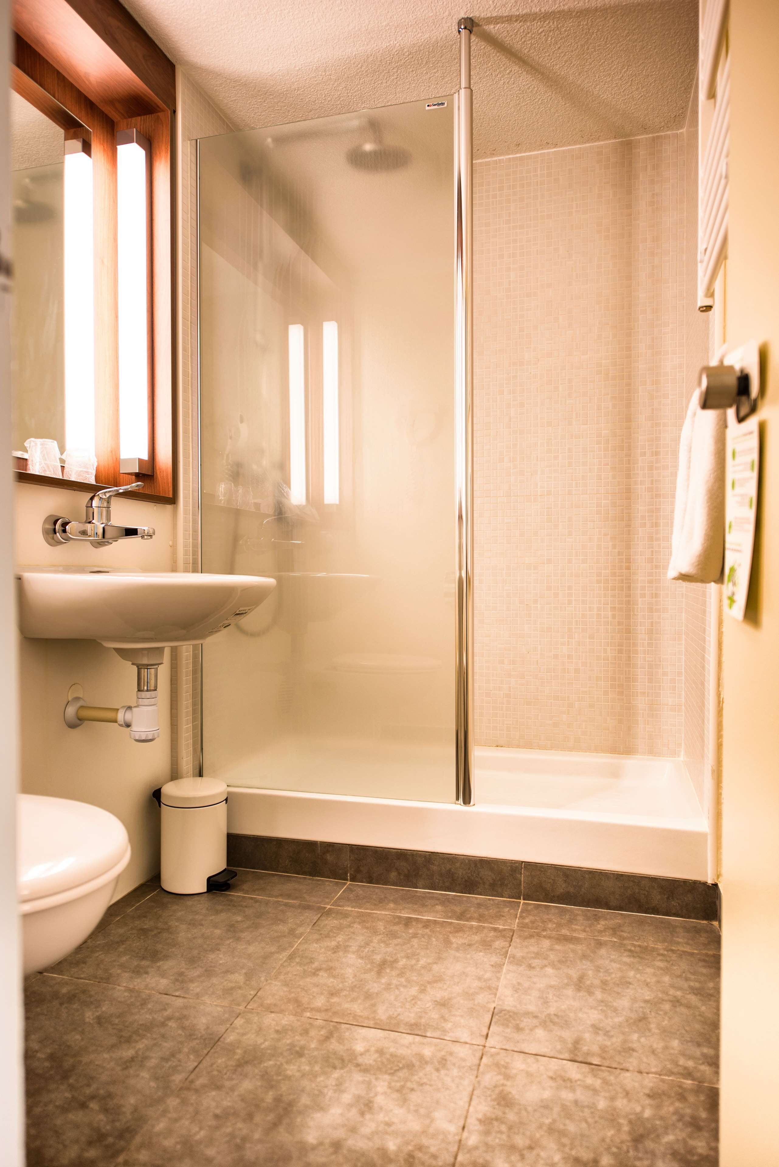 A bathroom with a glass-enclosed shower, a sink, and a toilet.