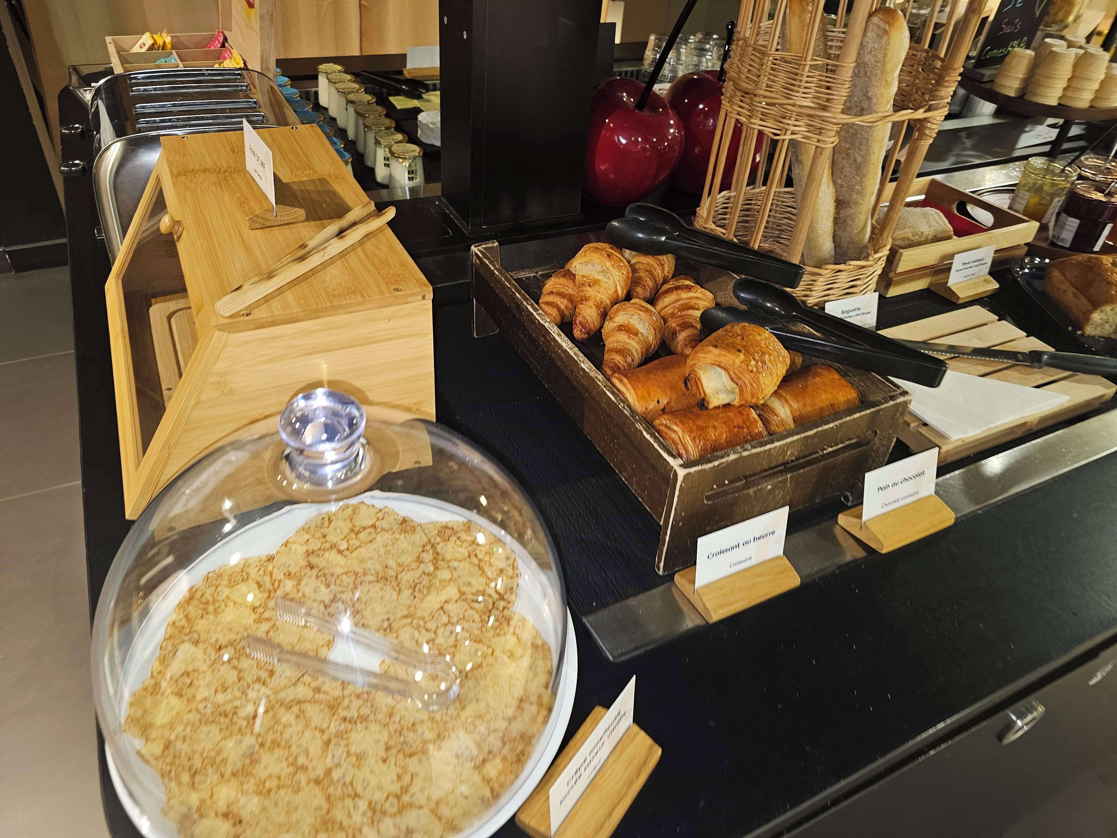 A bakery display with various pastries and bread, including croissants and baguettes, with labels indicating different types.
