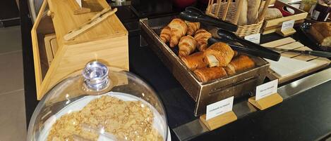 A bakery display with various pastries and bread, including croissants and baguettes, with labels indicating different types.