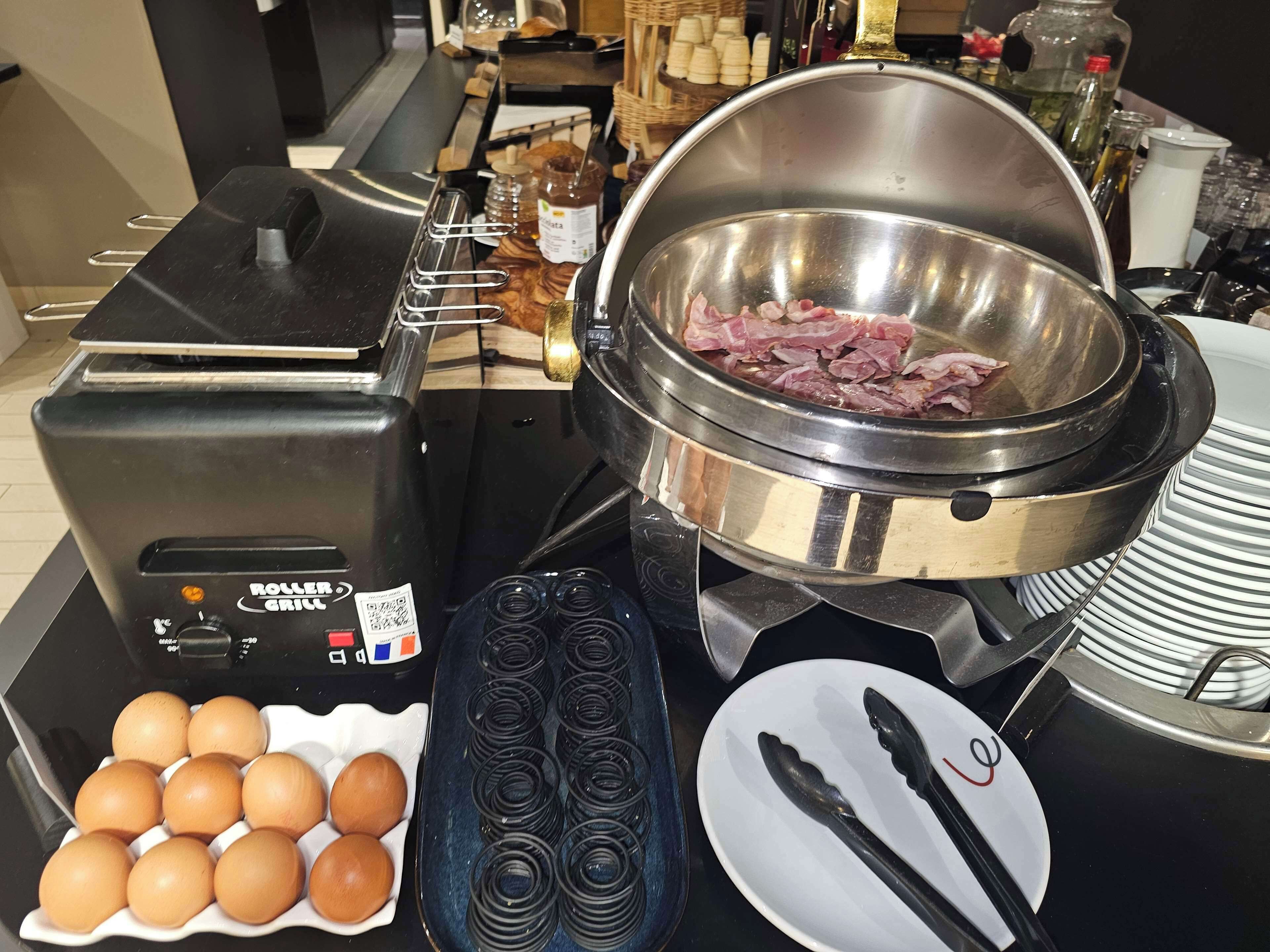 A breakfast setup with a toaster, a bowl of raw meat, eggs, and condiments.
