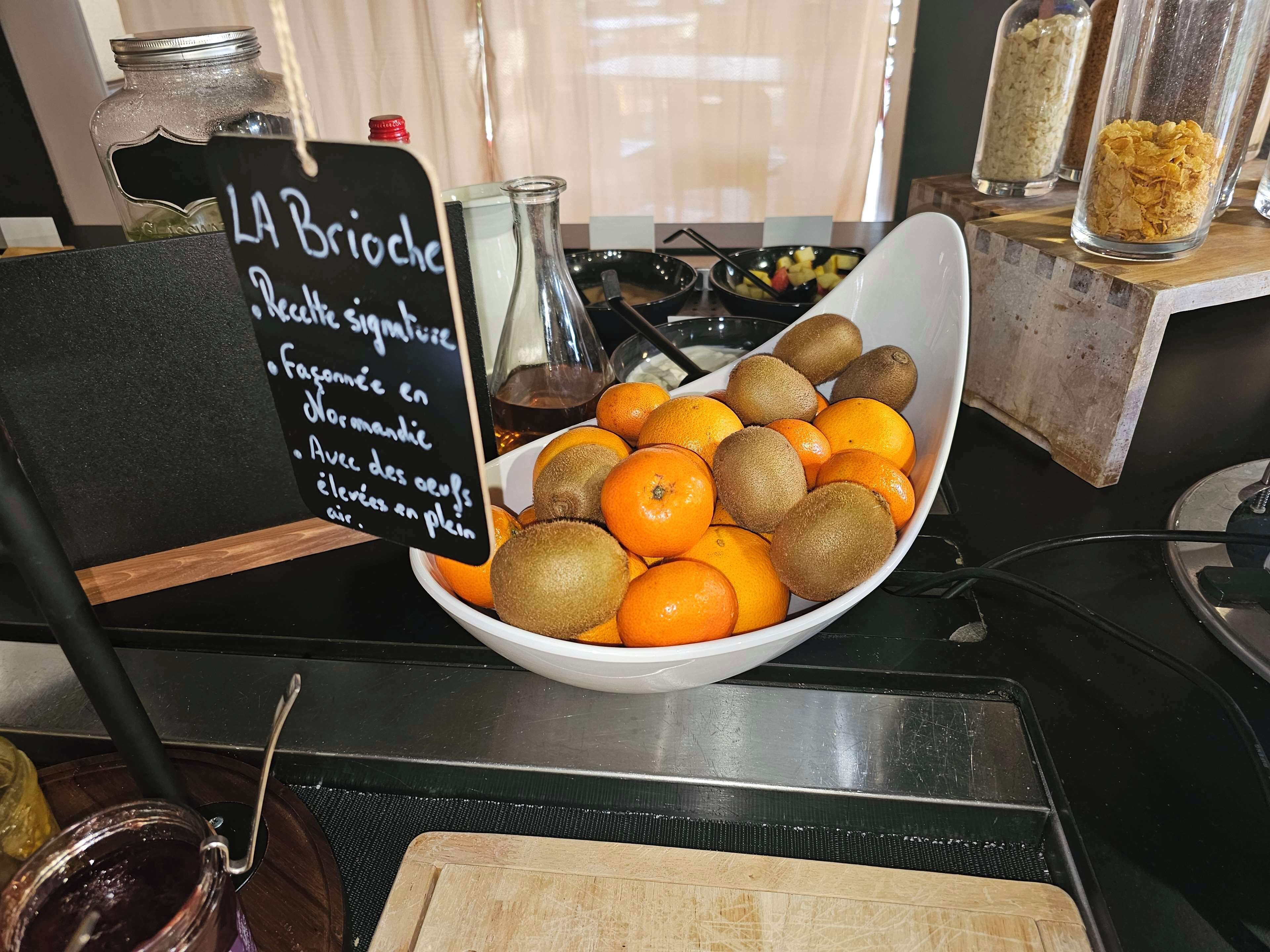 Un tazón con naranjas y kiwis sobre una mesa con un cartel.
