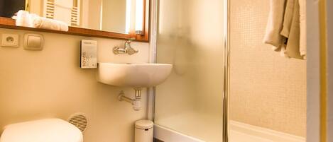 A bathroom with a toilet, sink, and glass shower enclosure.