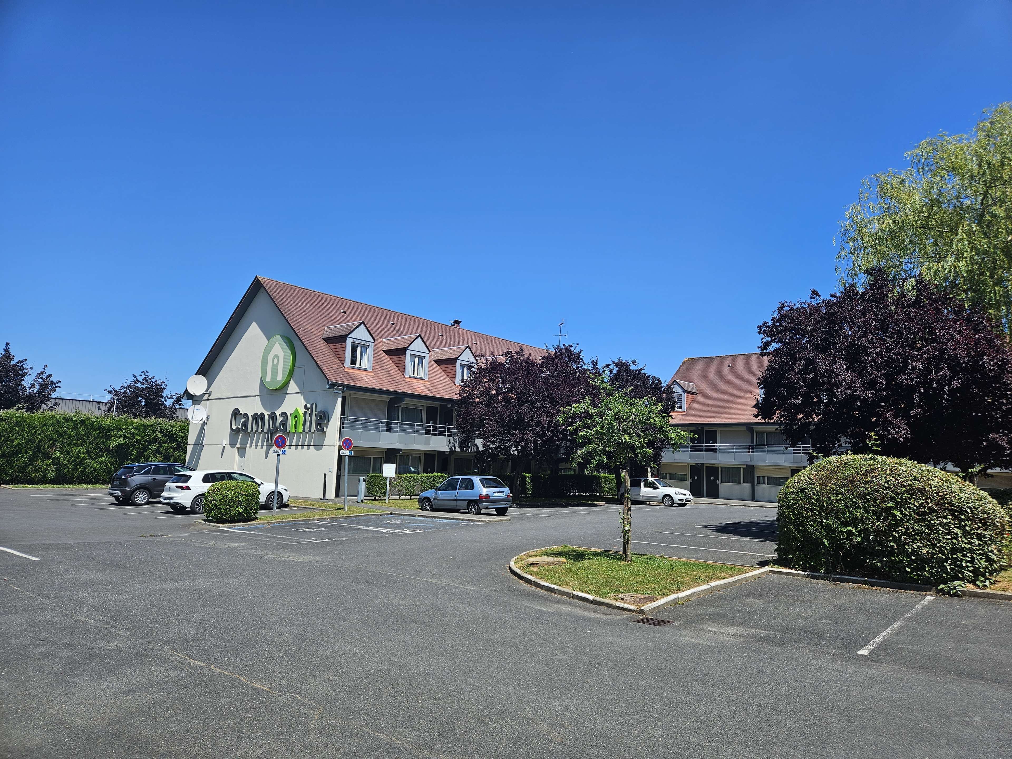 A commercial building with a sign reading "campanile" and a parking lot with several cars.