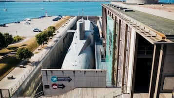 A large ship docked at a port with a sign indicating an aquarium and exhibition nearby.