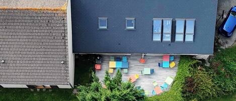 Een gebouw met twee verdiepingen, een plat dak, een bakstenen gevel en een kleine tuin met kleurrijk tuinmeubilair.