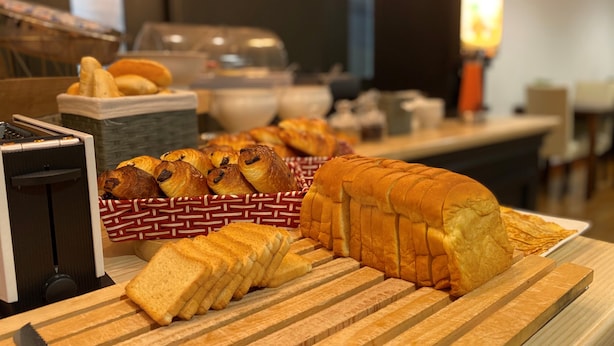 A breakfast buffet with bread, pastries, and a coffee machine.