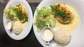 Two plates of food with rice, vegetables, and a creamy sauce.