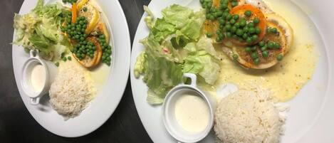 Dos platos de comida con arroz, verduras y salsa cremosa.