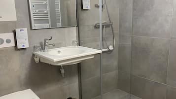 Une salle de bain moderne avec une douche à parois de verre, un lavabo blanc et des toilettes.