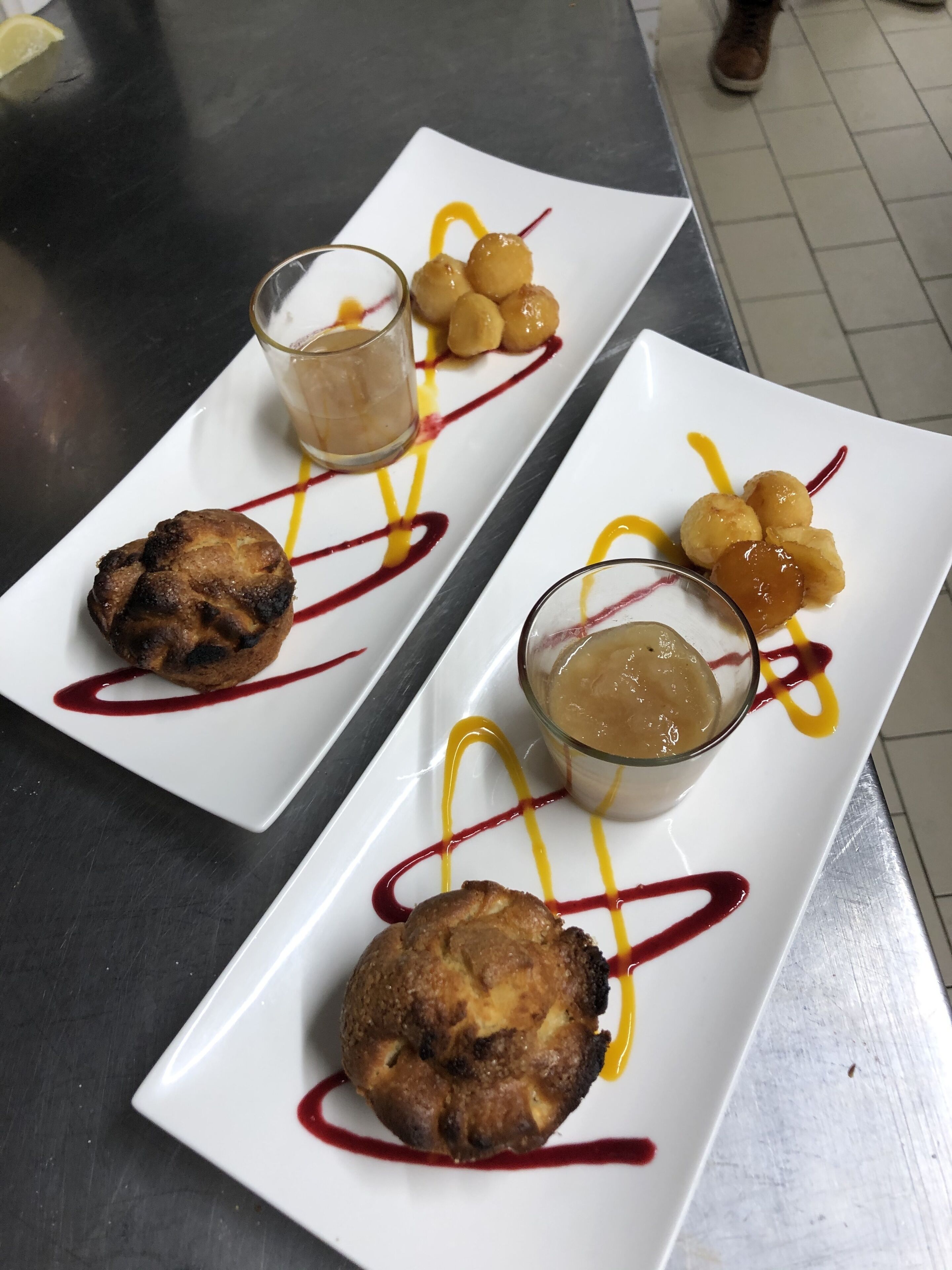 A dessert plate with a muffin, a glass of dessert, and a small bowl of sauce.