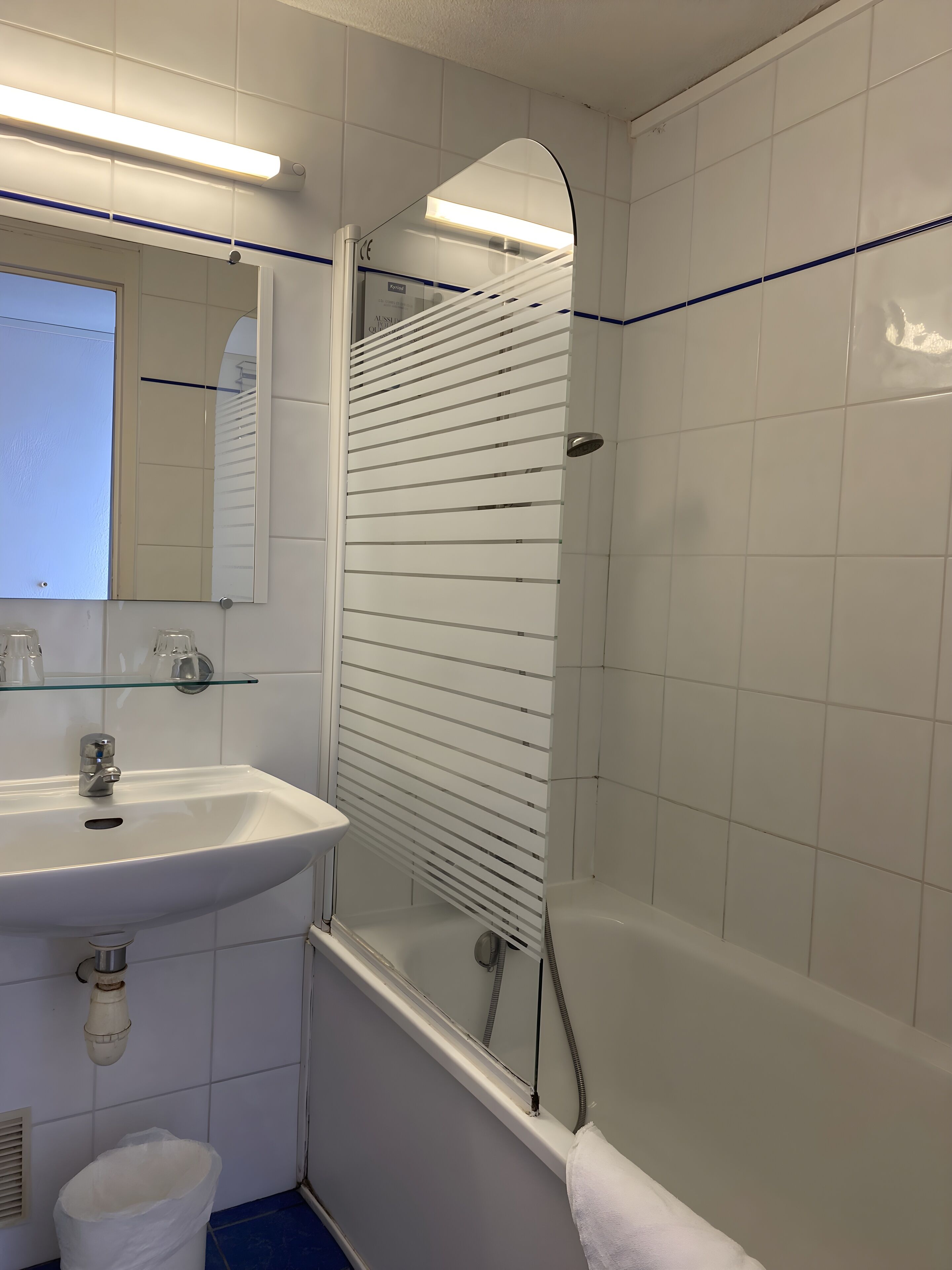 Een badkamer met een wit wastafelmeubel, spiegel en douchecabine.