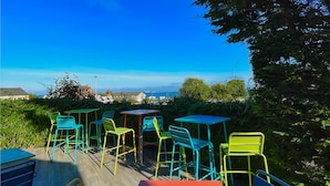 An outdoor seating area with colorful metal chairs and tables, overlooking a scenic view.