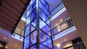Un atrio de varios niveles con barandillas de cristal y un ascensor central.