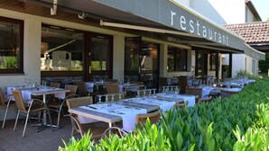 Un restaurante al aire libre con mesas dispuestas para comer, rodeado de vegetación.