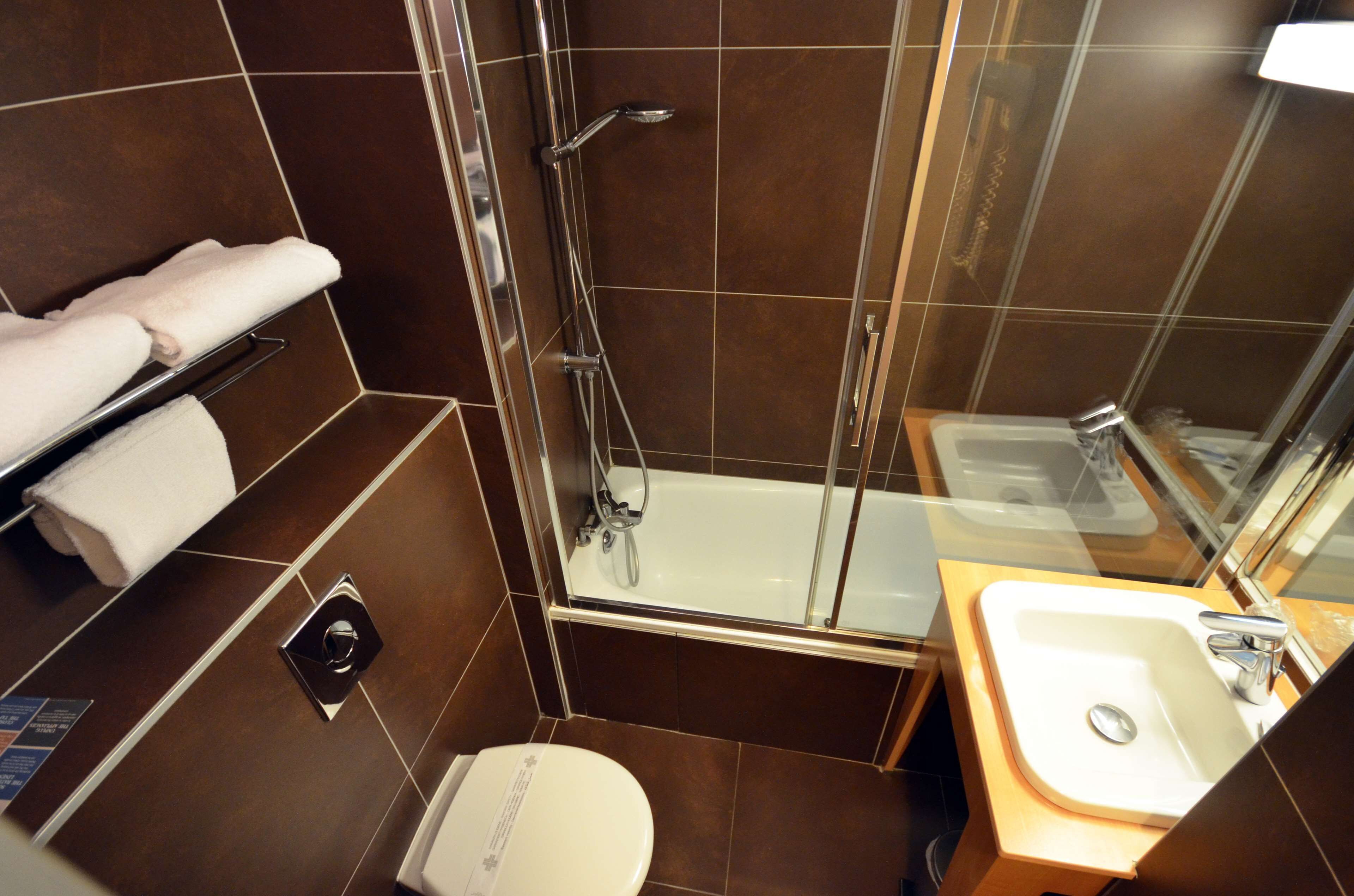 A small, modern bathroom with a glass-enclosed shower, a white toilet, and a wooden vanity with a sink.
