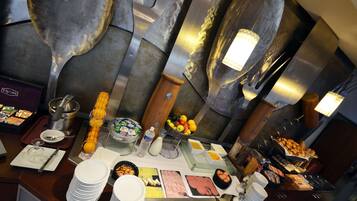 Montaje de bufé con diversas opciones de comida, utensilios y una pared decorativa.