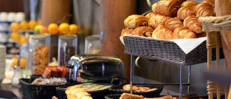 A buffet with various baked goods, including croissants and bread, arranged on a counter.