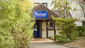 La entrada de un hotel con un letrero que dice 'Kyriad Hotel Restaurant'.