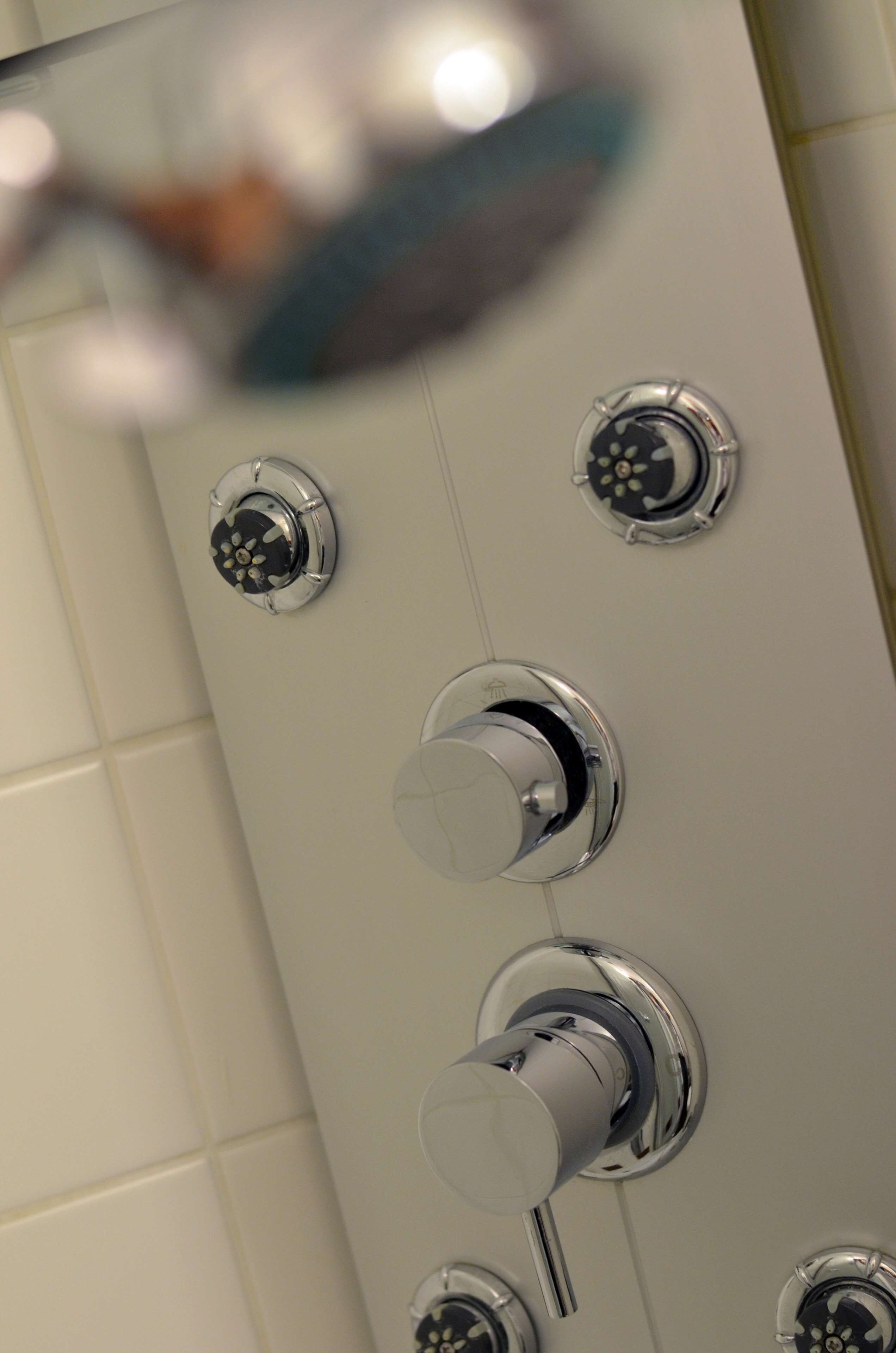 A shower with multiple chrome fixtures and a control knob.