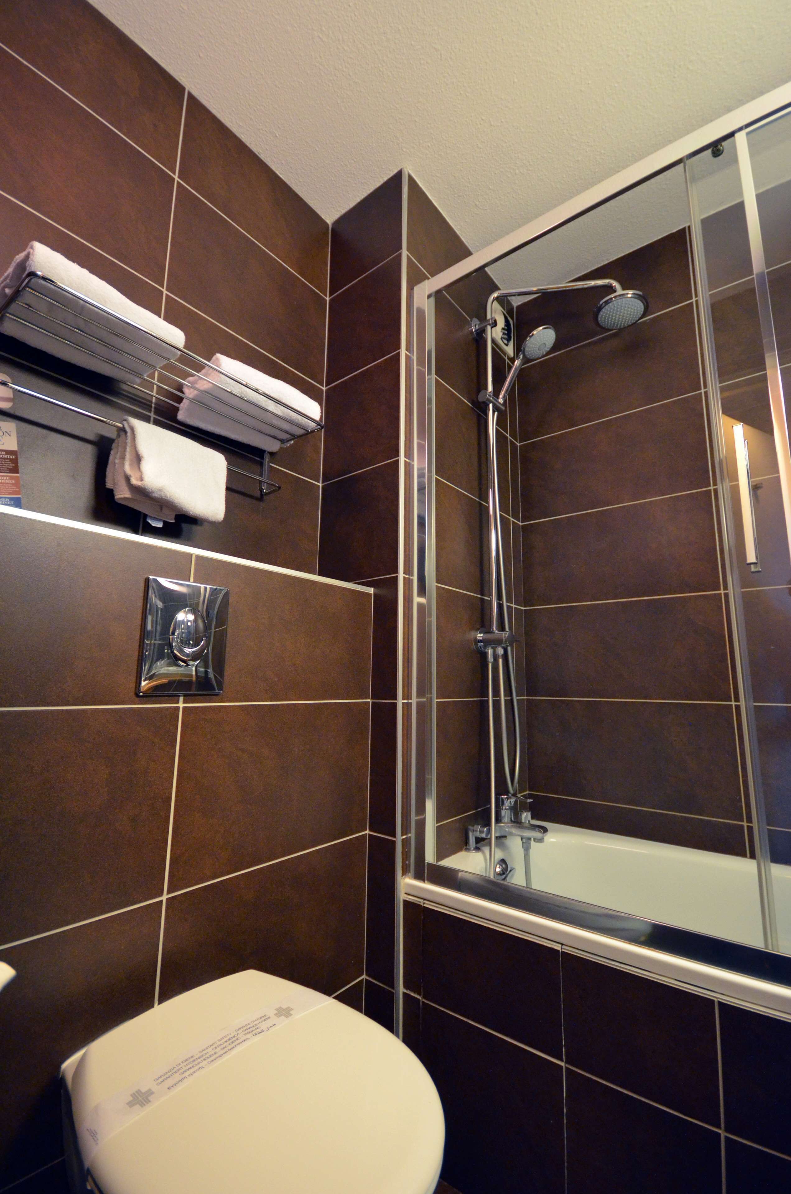Un baño con ducha, inodoro y barra para toallas.