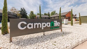 A sign for Campanile Nature with a gravel ground and trees. - Campanile NATURE - Clermont Ferrand Nord Riom (Riom)