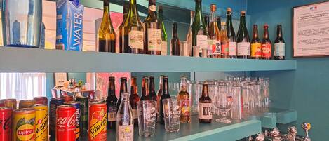 Un bar con estantes llenos de diversas botellas de licores y latas de bebidas.