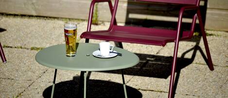A table with a beer can and a cup, and a red chair in the background.