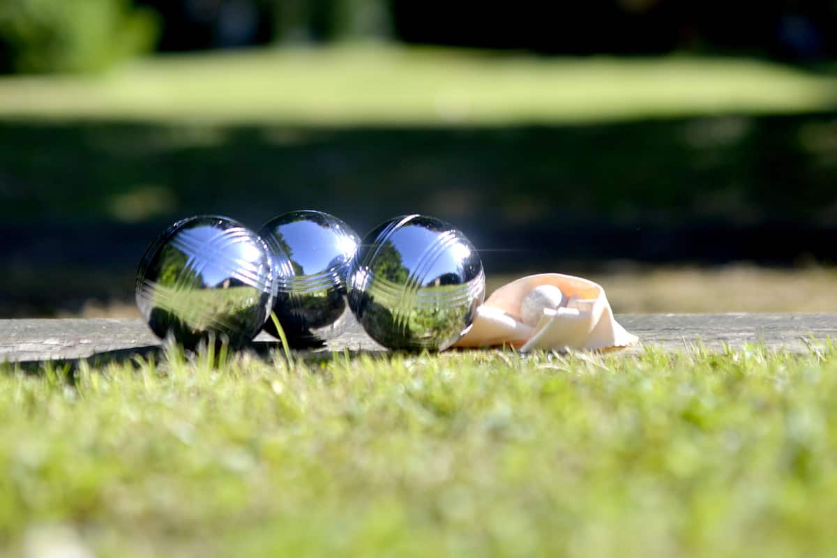 Drei reflektierende Kugeln auf einer grasbewachsenen Fläche, verschwommener Grünflächenhintergrund.