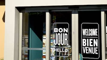 A building with a large 'K' sign and a window displaying 'BON JOUR HELLO' and 'WELCOME BIENVENUE'.