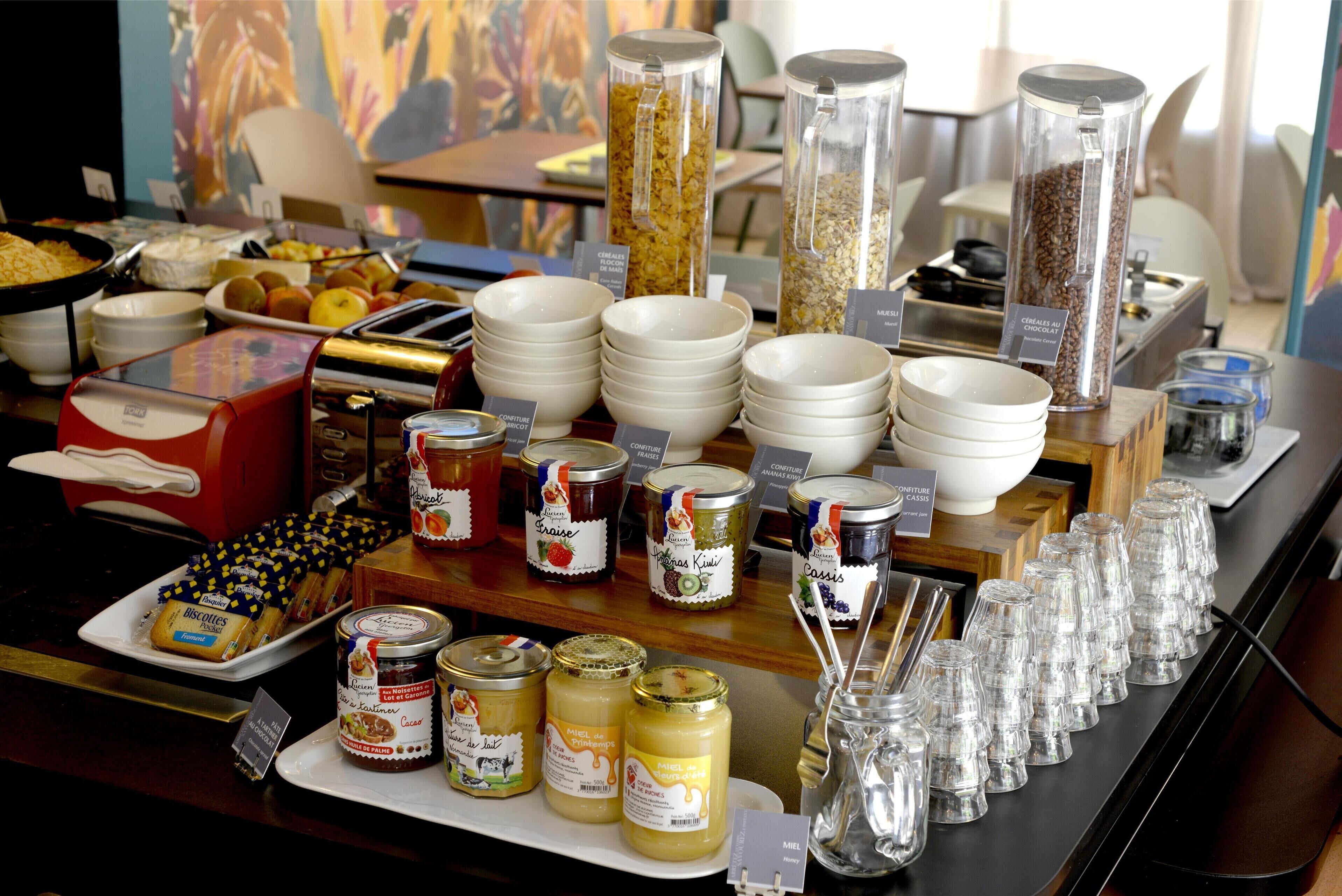 A buffet setup with various food items, including jars of preserves and a selection of fruits and pastries.