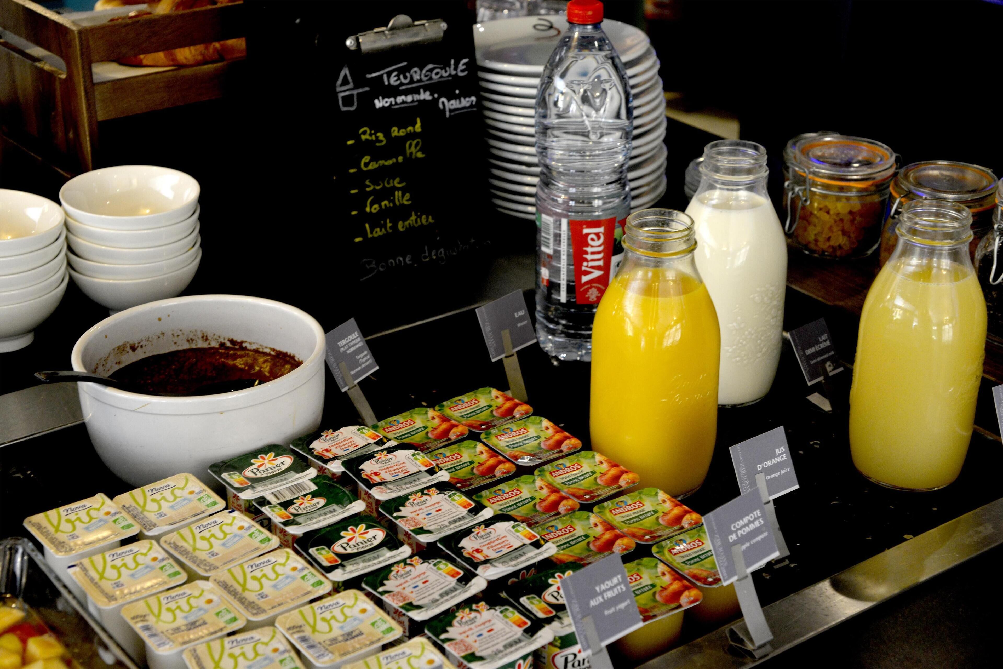 A buffet with various food items, including yogurt, juice, and a bowl of soup.