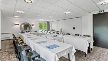 Ein Konferenzraum mit langen Tischen, Stühlen und einem großen Spiegel.
