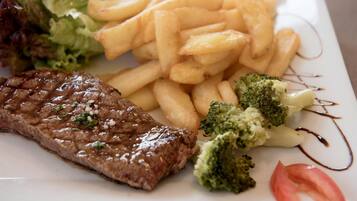 A plate with steak, fries, broccoli, and a tomato slice.