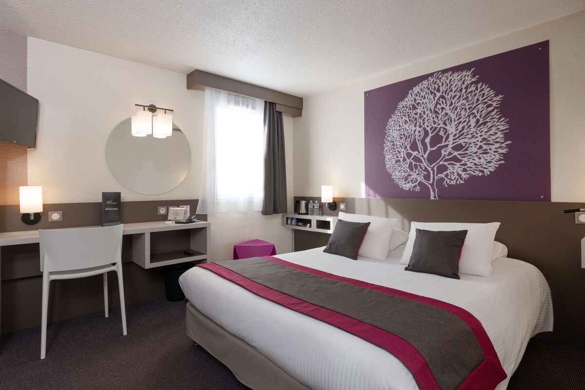 Habitación de hotel con cama, escritorio, silla y una obra de arte grande en la pared.
