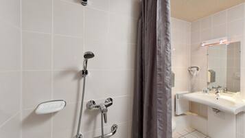 Een moderne badkamer met een douche, wastafel en spiegel.