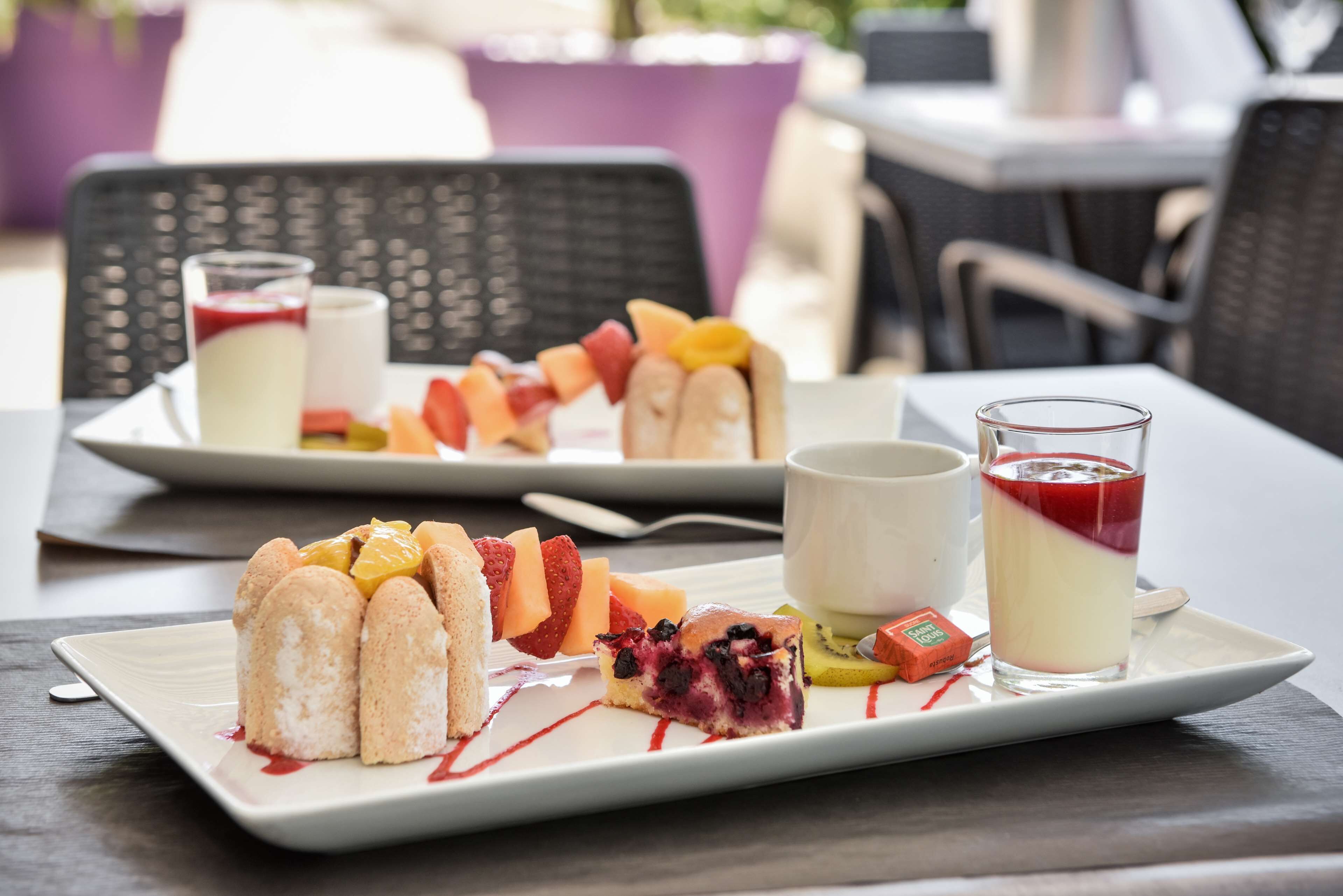 Un plato de postre con diversas frutas y un vaso de un postre en capas.