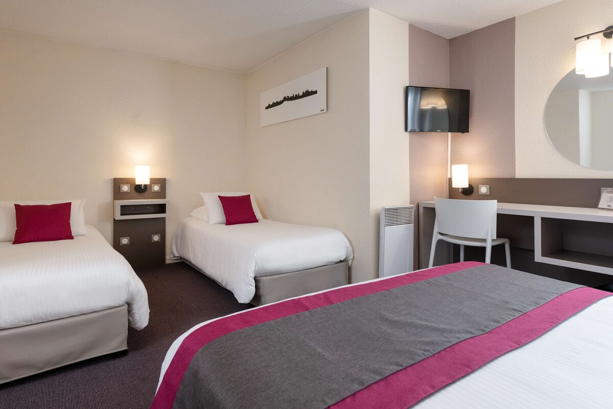 Habitación de hotel con dos camas, un escritorio, una silla, un televisor y un espejo.