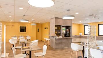 Un restaurante moderno con suelo de madera, sillas blancas y una zona de bar central.