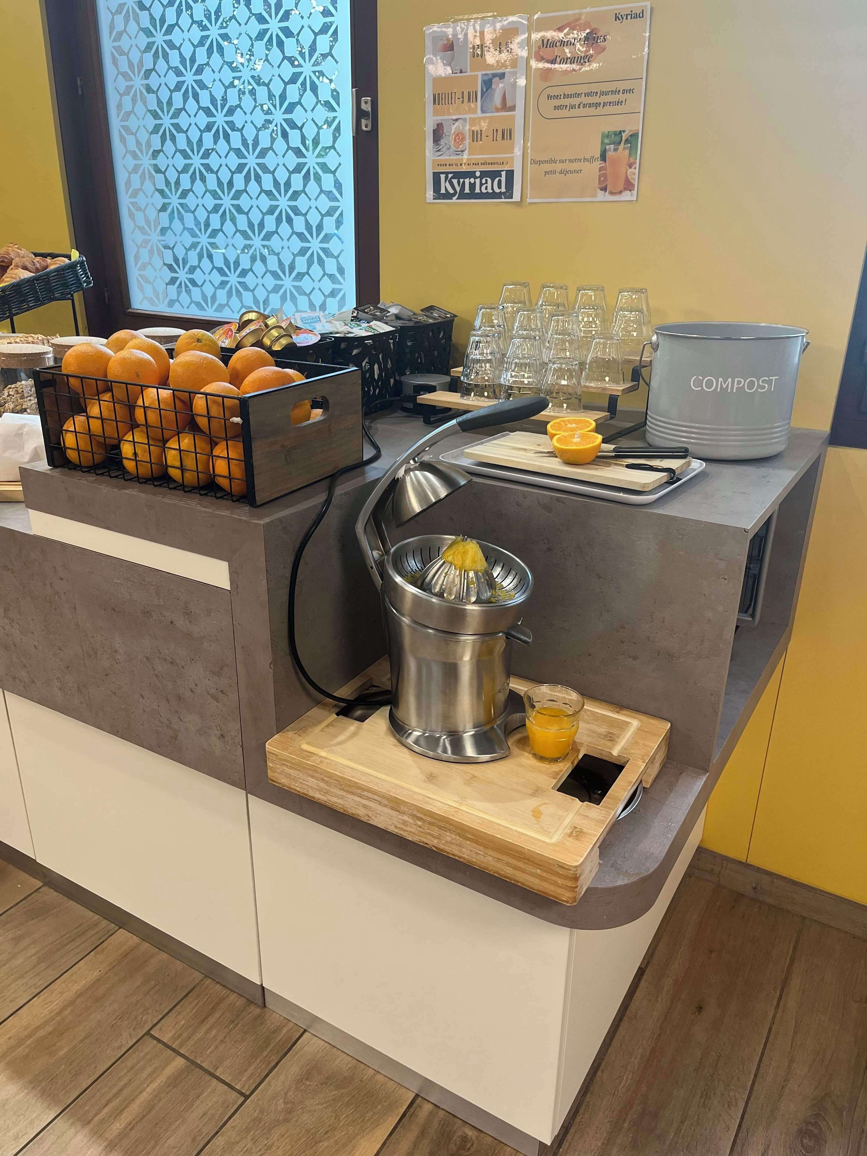 Ein Frühstücksbuffet mit Entsafter, Orangenscheiben und einer Komposttonne.
