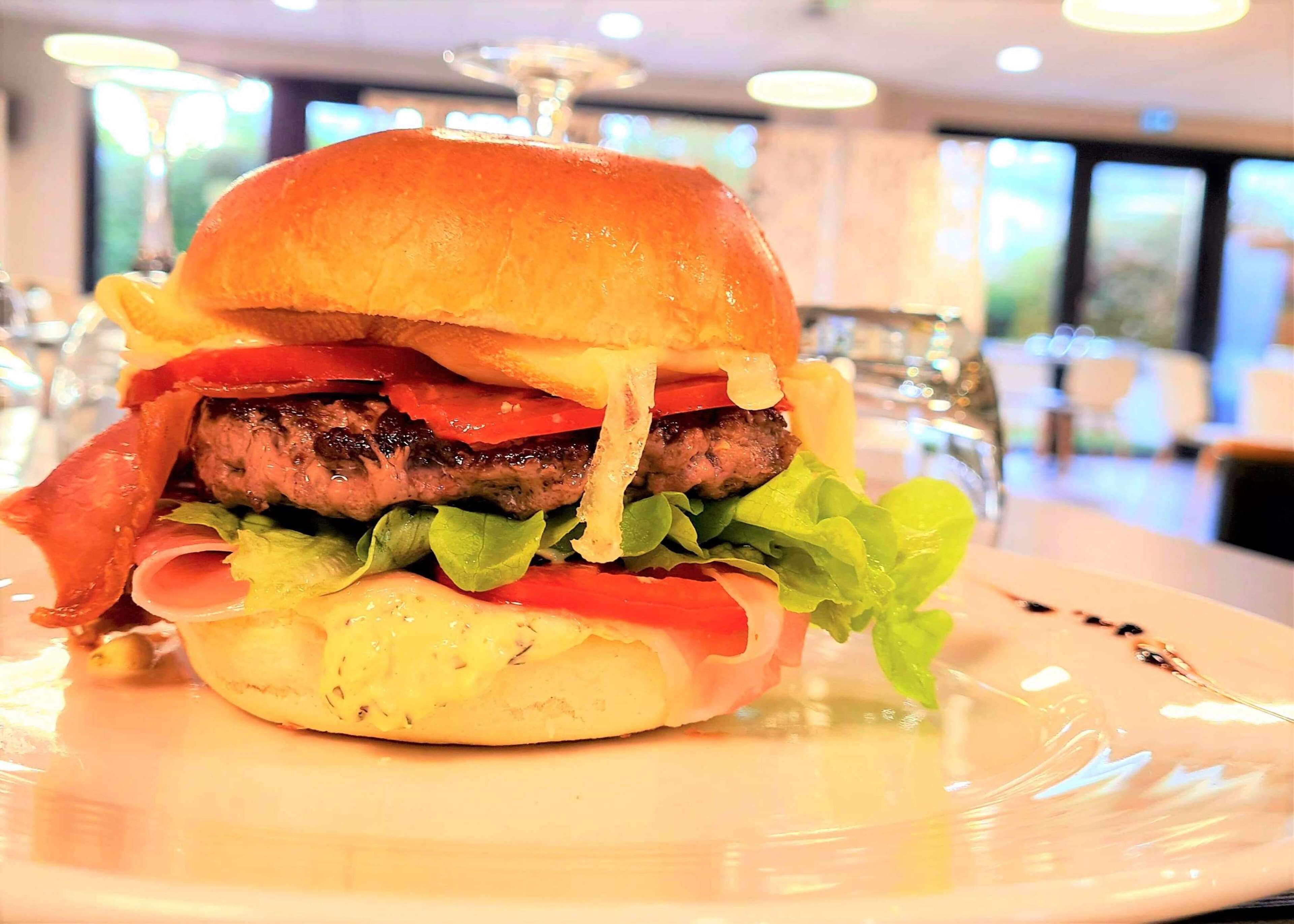 Ein Burger mit Salat, Tomate und Speck auf einem Teller.
