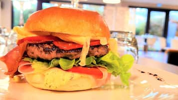 A burger with lettuce, tomato, and bacon on a plate.