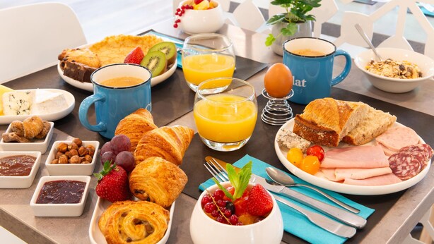 A breakfast table with croissants, fruit, eggs, and juice.