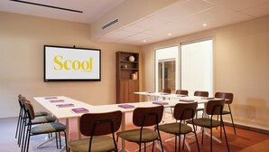 A conference room with a large screen displaying 'Scoo by SONIDO', a white table, and several chairs. - Hotel des Victoires by Soniho (Cannes)