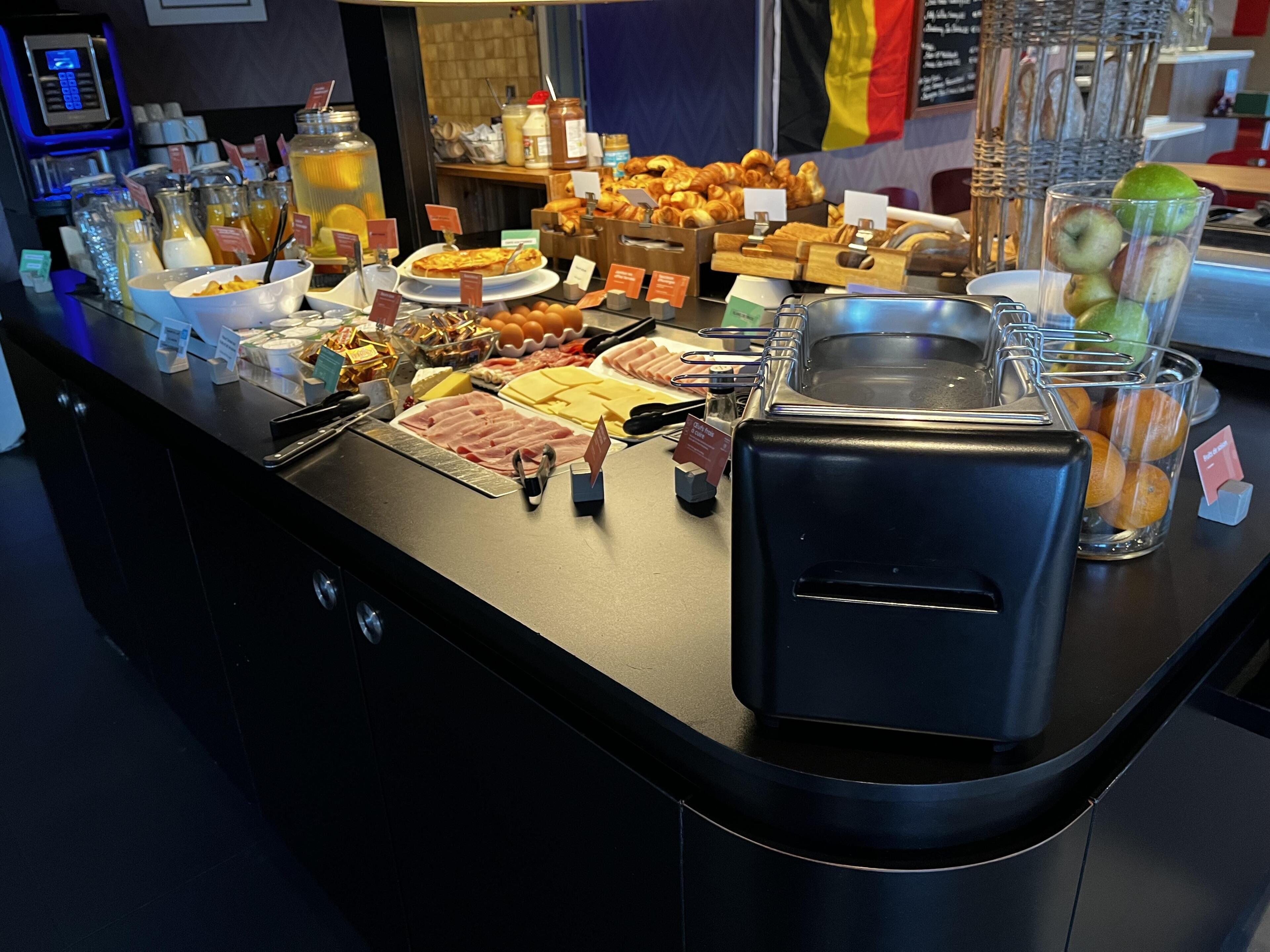 A buffet counter with various food items, a beverage dispenser, and a sink.