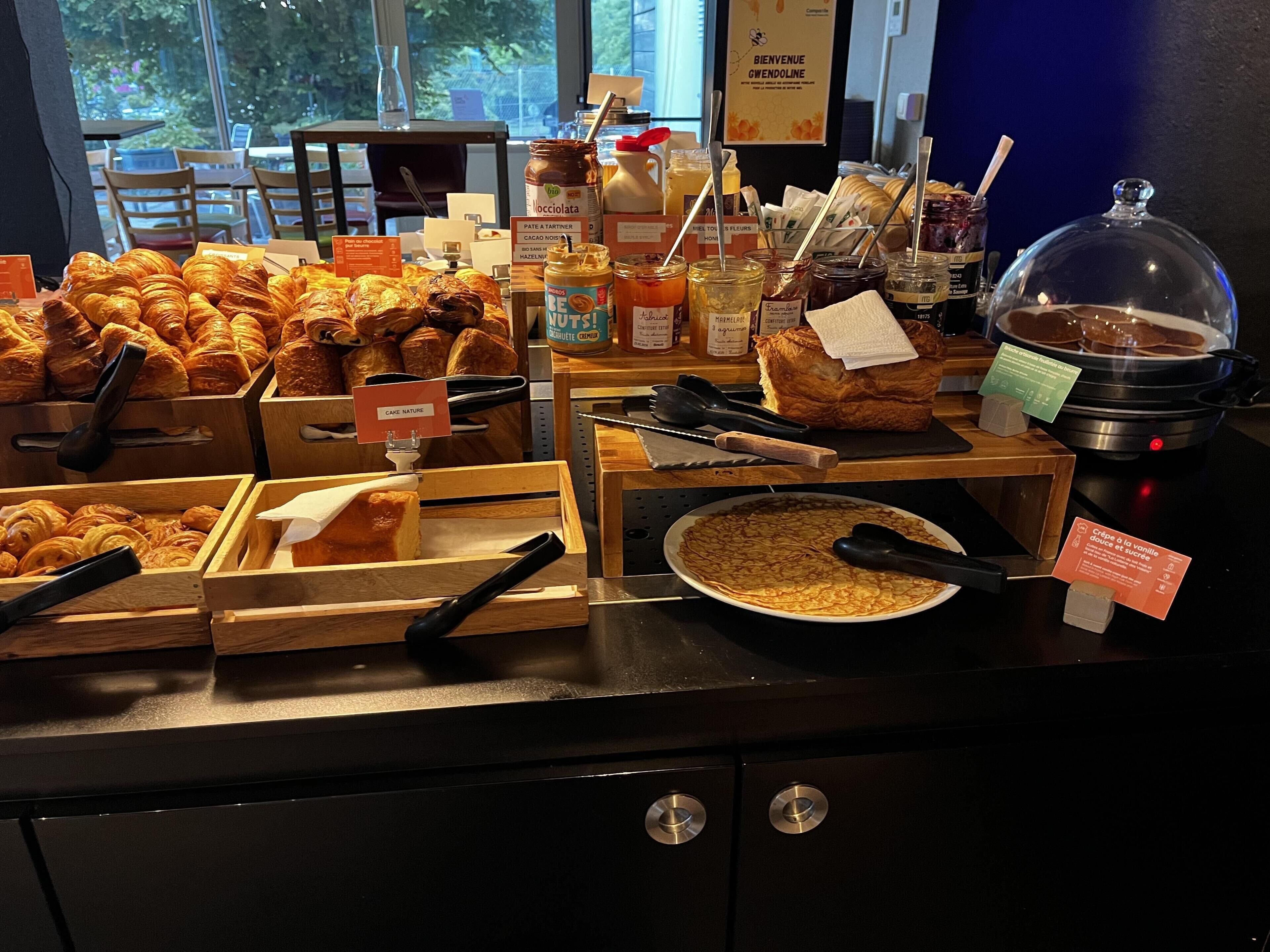 A breakfast buffet with various pastries, jams, and a hot food station.