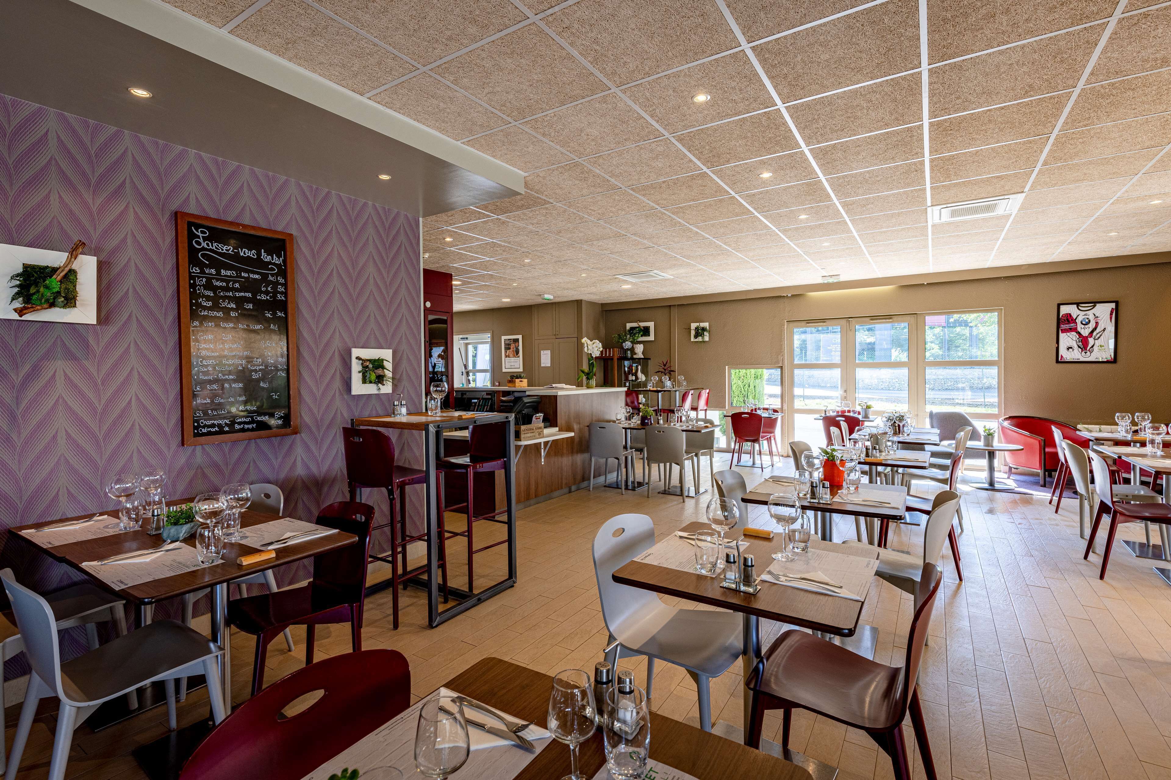 A restaurant with a chalkboard menu, wooden tables, and chairs.